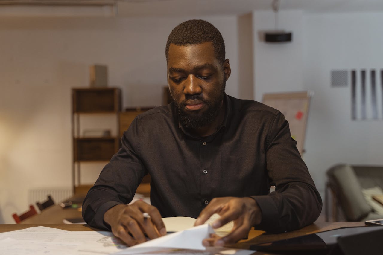 A mature businessman in a creative office environment reviewing financial documents.